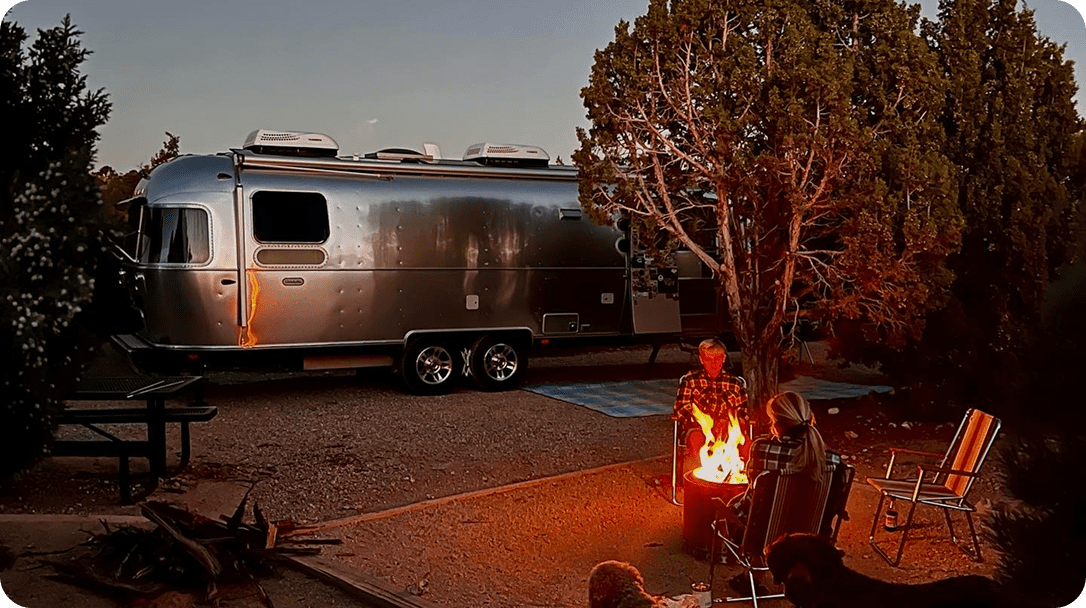 Evening campfire by parked Airstream trailer